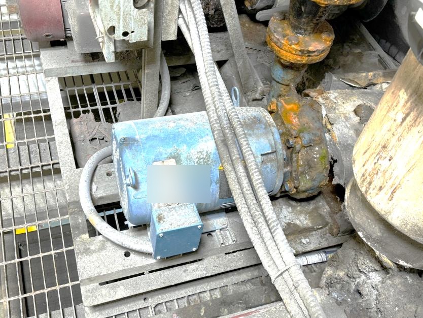 Blue 3-phase industrial motor with junction box and conduit in harsh plant environment — typical equipment inspected during vibration analysis