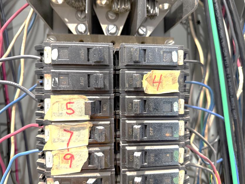 Breaker panel with hand-written yellow tape labels identifying circuits — typical field conditions during electrical thermography inspection